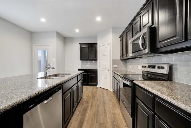 a kitchen with stainless steel appliances granite countertop a stove a sink and a microwave