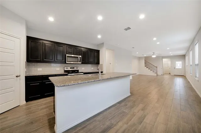 a large kitchen with stainless steel appliances lots of counter space and wooden floor