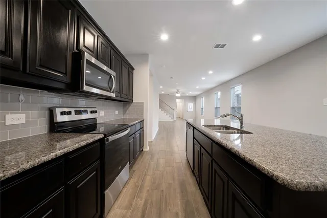 a large kitchen with granite countertop stainless steel appliances and wooden cabinets