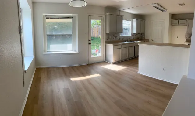an empty room with wooden floor and windows
