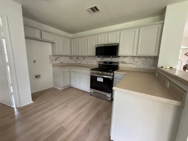 a kitchen with stainless steel appliances a stove refrigerator sink and microwave