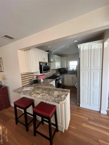 a kitchen with stainless steel appliances granite countertop a table chairs sink refrigerator and cabinets