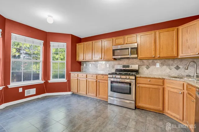 a kitchen with stainless steel appliances granite countertop a stove a sink and a microwave