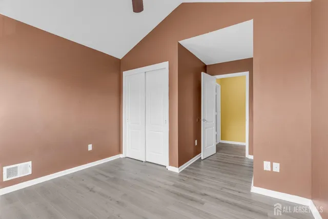 a view of an empty room with closet and a window