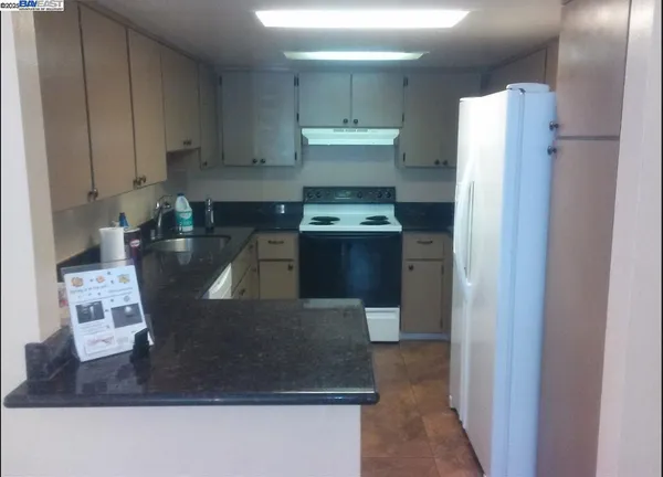 a kitchen with stainless steel appliances granite countertop a refrigerator a stove and a sink