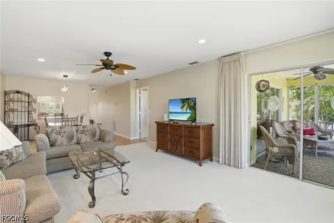 a living room with furniture and a flat screen tv with kitchen view