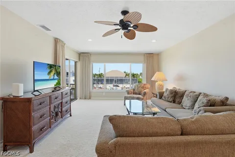 a living room with furniture a ceiling fan and a large window