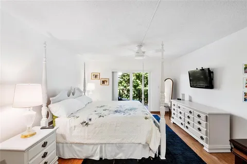 a bedroom with a bed a flat tv screen and a dresser