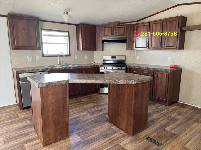 a kitchen with stainless steel appliances granite countertop wooden cabinets a sink a stove a refrigerator and island