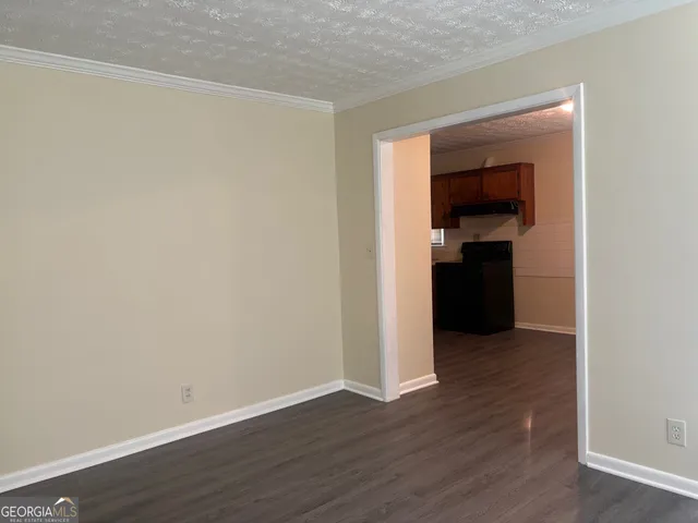 a view of an empty room with wooden floor & cabinets