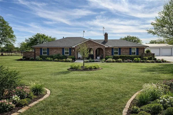 a front view of a house with garden and trees