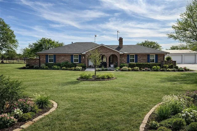 a front view of a house with garden and trees