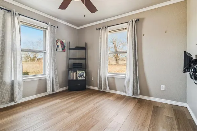 a view of an empty room with a window and wooden floor