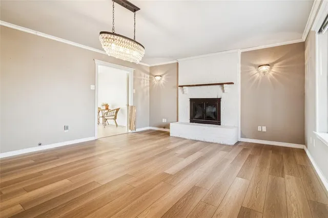 a view of an empty room with wooden floor fireplace and a window