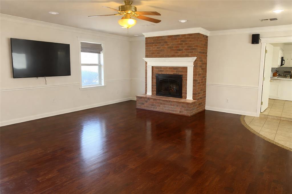 903 Houston Street Anna, TX 75409 - Photo 8 of 27 a view of an empty room with wooden floor and a fireplace