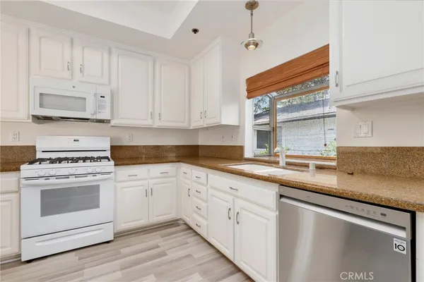 a kitchen with granite countertop white cabinets and white appliances
