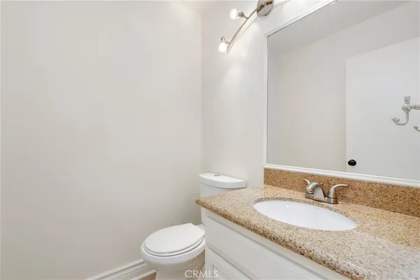 a bathroom with a granite countertop sink a toilet and a mirror