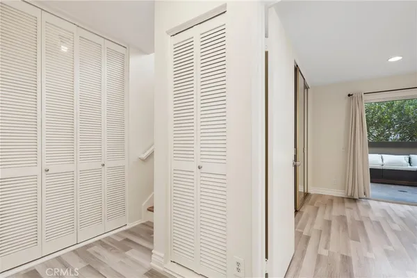 a view of a hallway with wooden floor and a bathroom
