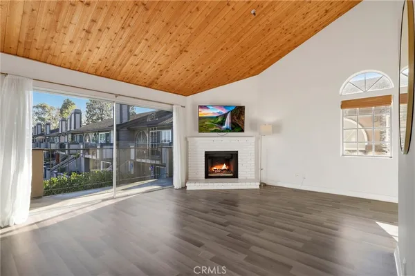 a view of an empty room with wooden floor fireplace and a window