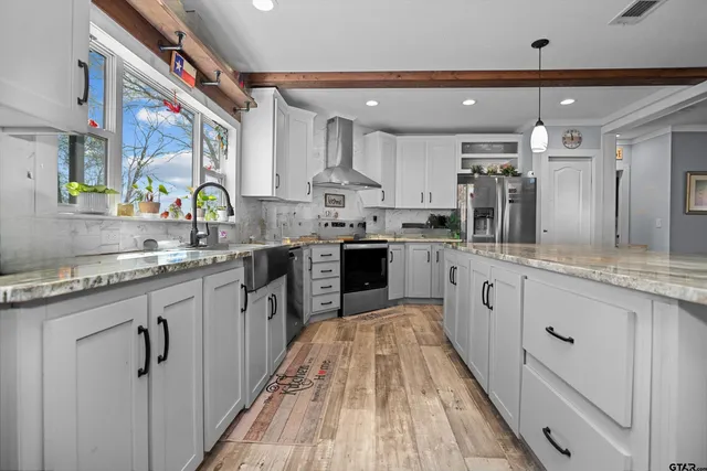 a kitchen with stainless steel appliances granite countertop a stove top oven a sink dishwasher a dining table and chairs with wooden floor