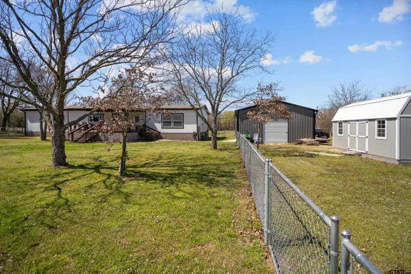 a backyard of a house with plants and barbeque oven
