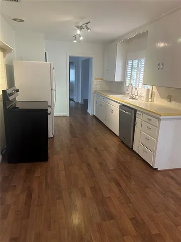 a large kitchen with kitchen island wooden floors and stainless steel appliances