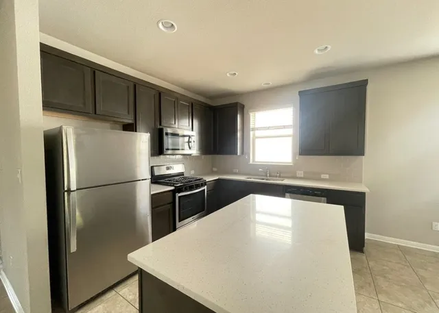 a kitchen with stainless steel appliances a refrigerator a sink a stove a microwave a counter space and cabinets