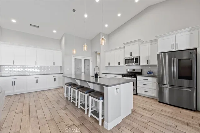 a kitchen with white cabinets appliances and wooden floor
