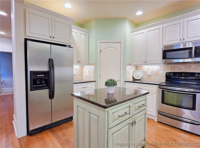 a kitchen with stainless steel appliances granite countertop a refrigerator a stove and a sink with wooden floor