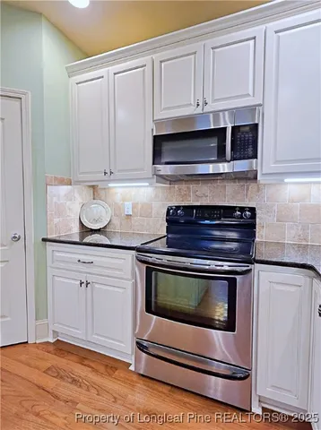 a kitchen with granite countertop white cabinets and appliances