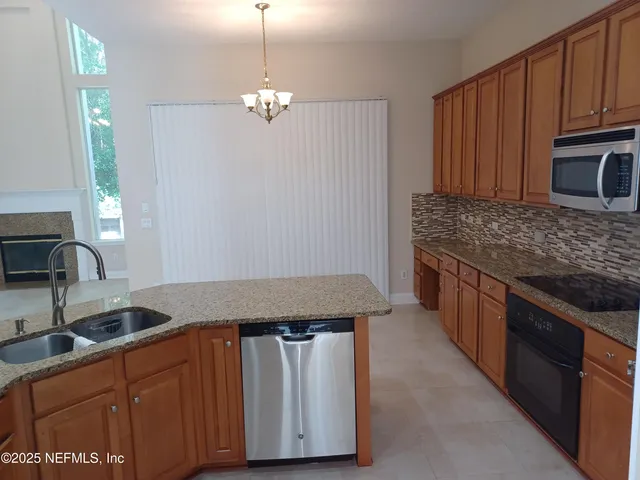 a kitchen with granite countertop a sink cabinets and stainless steel appliances