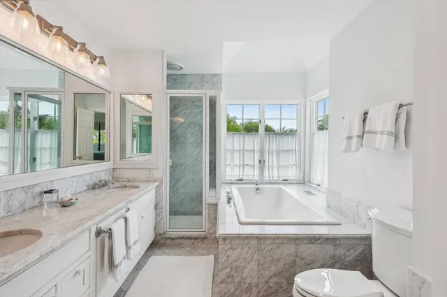 a bathroom with a granite countertop sink mirror vanity bathtub and toilet