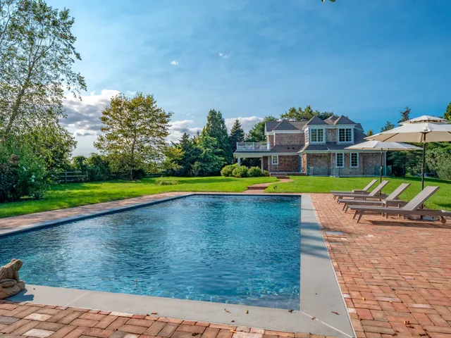 a view of a swimming pool with lawn chairs and a big yard