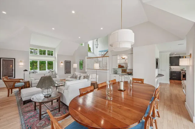 a dining room with wooden floor a chandelier a glass table and chairs