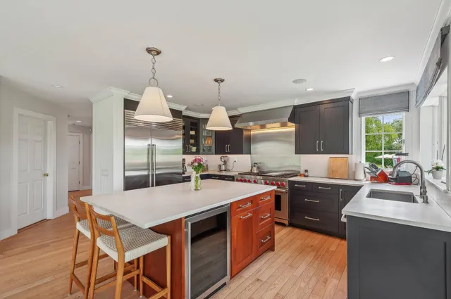 a kitchen with stainless steel appliances granite countertop a stove a sink dishwasher a dining table and chairs with wooden floor