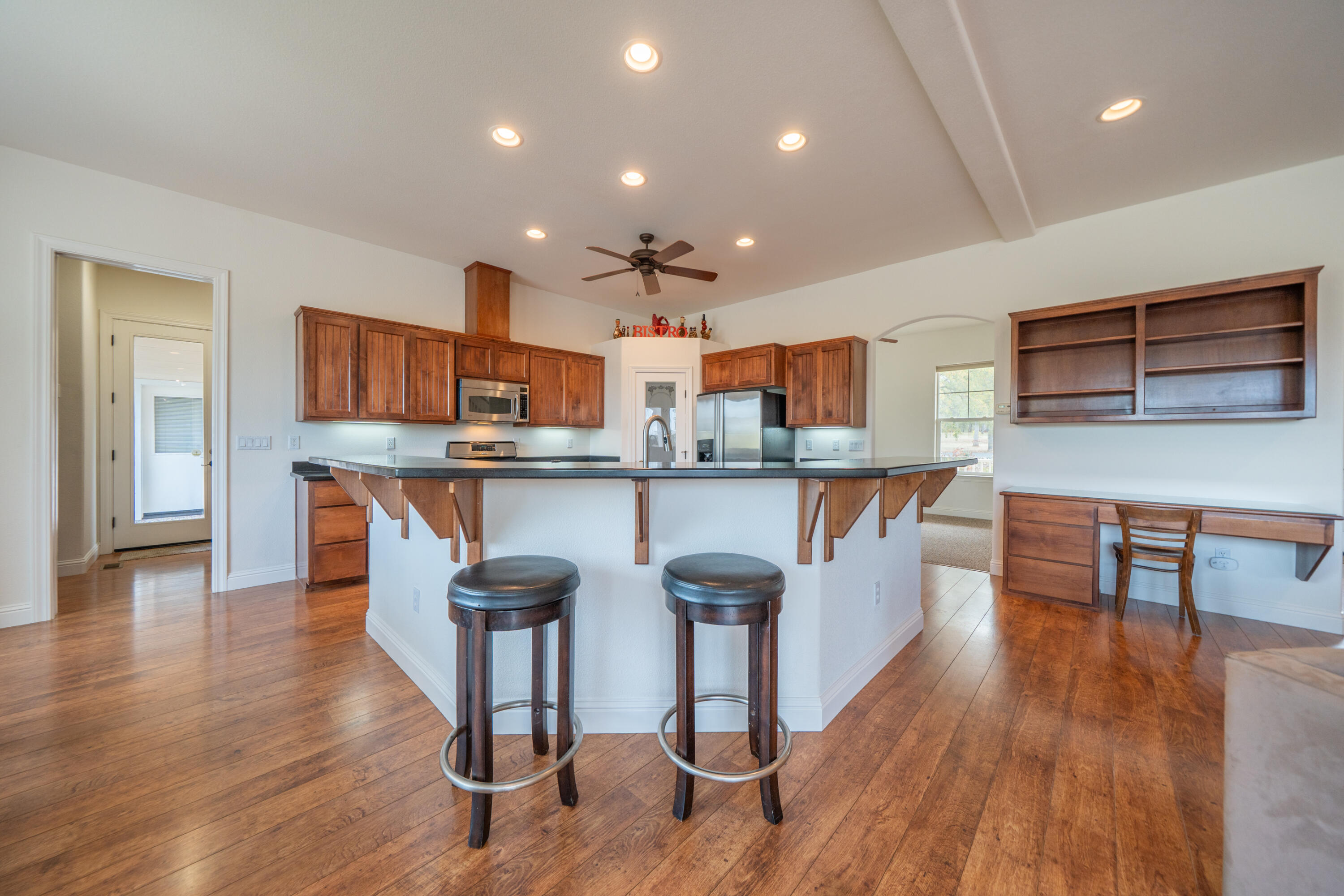8180 Whispering Oaks Road Redding, CA 96002 - Photo 18 of 100 a kitchen with stainless steel appliances kitchen island granite countertop wooden floors and cabinets