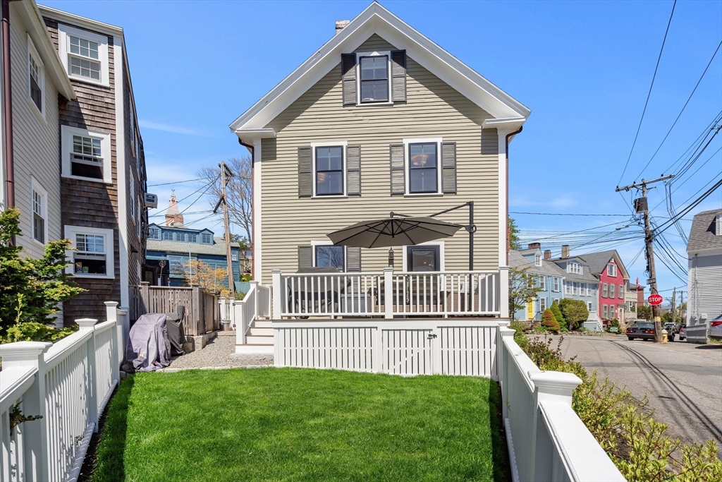 1 Gregory Street Marblehead, MA 01945 - Photo 5 of 42 a front view of a house with a yard table and chairs