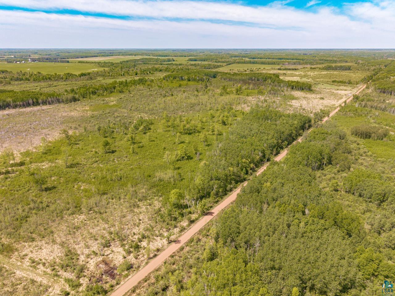 6606 Metso Road Kettle River, MN 55757 - Photo 46 of 84 Expansive undeveloped land with a visible dirt road, featuring varied green foliage and distant clearings