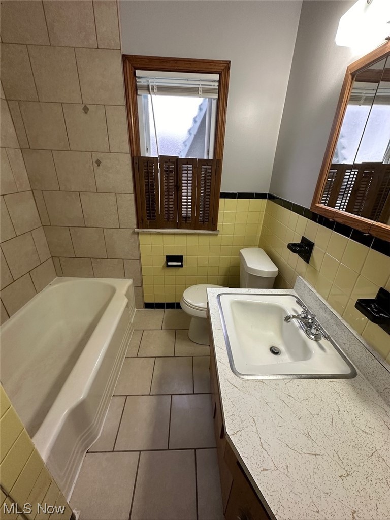 4994 North Barton Road Cleveland, OH 44124 - Photo 16 of 28 Bathroom featuring backsplash, tile walls, vanity with extensive cabinet space, tile floors, and toilet