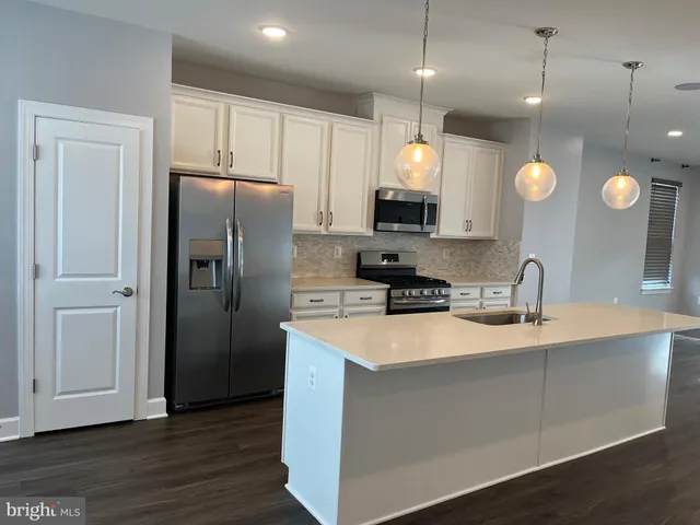 a kitchen with stainless steel appliances granite countertop a refrigerator a oven and a sink with large countertops