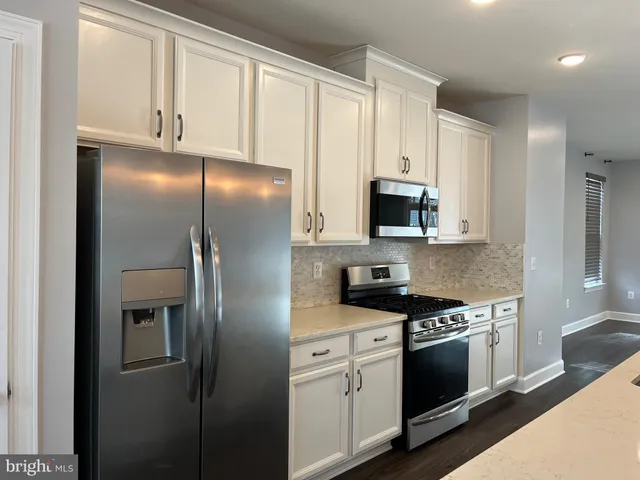 a kitchen with stainless steel appliances white cabinets and a stove top oven