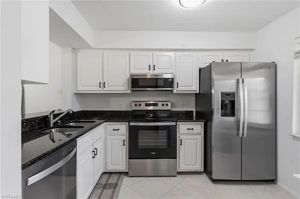 a kitchen with stainless steel appliances granite countertop a refrigerator a stove and a sink with granite countertops