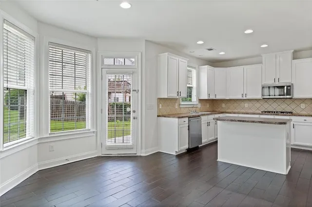 a kitchen with granite countertop white cabinets and wooden floor