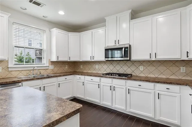 a kitchen with granite countertop white cabinets and a sink