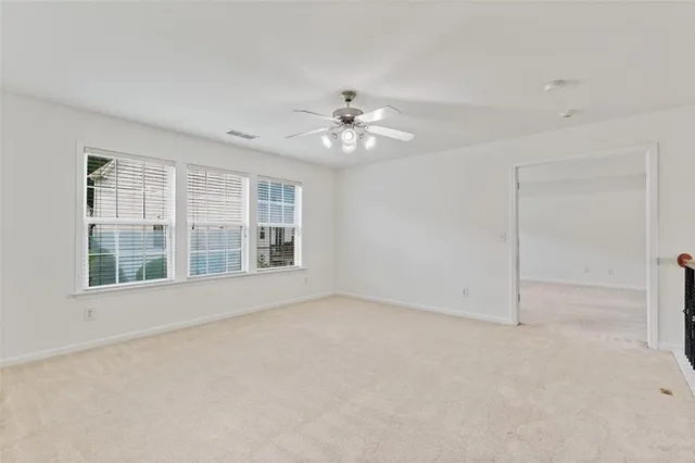 an empty room with chandelier fan and windows