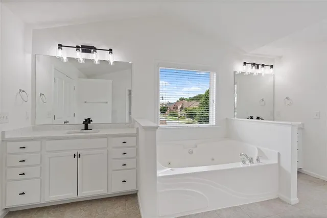a spacious bathroom with a tub sink and mirror