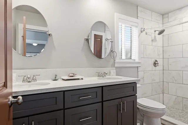 a bathroom with a double vanity sink mirror and toilet