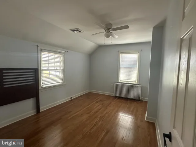 a view of a livingroom with wooden floor a ceiling fan and windows