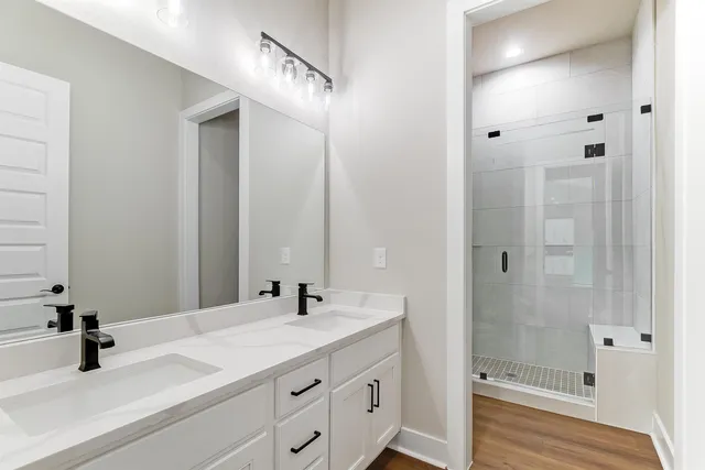 a bathroom with a double vanity sink a mirror and shower