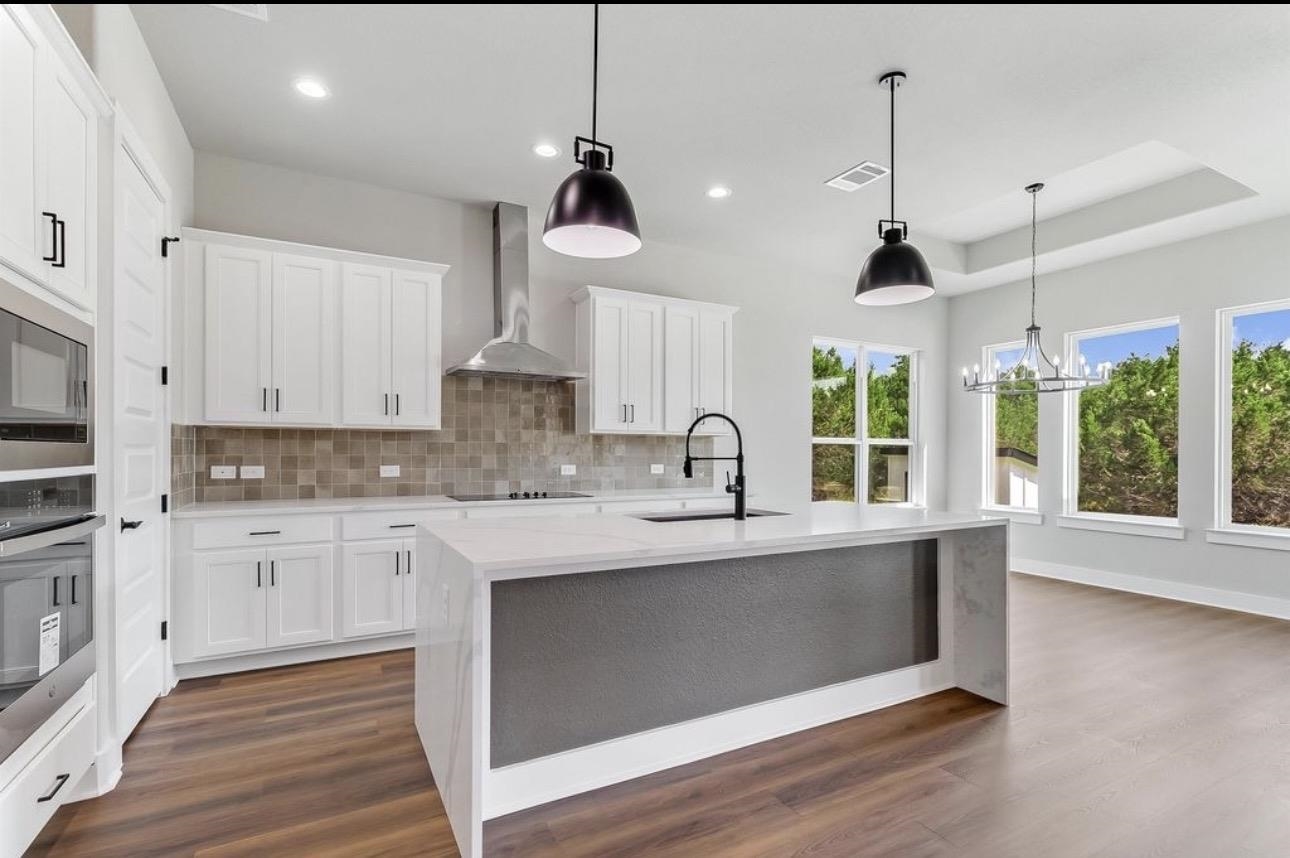 179 Rosebud Rnch Road Bertram, TX 78605 - Photo 6 of 28 a kitchen with stainless steel appliances granite countertop a sink a stove and a wooden floors